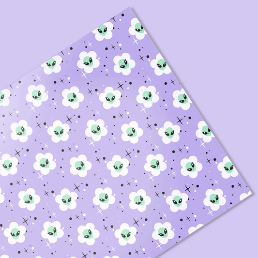 Floral patterned paper with cartoonish alien face flowers on a purple background